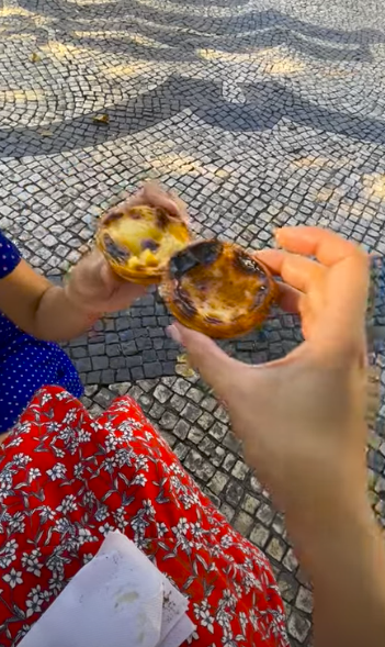 two hands cheers-ing with pastel de nata custard egg pastries