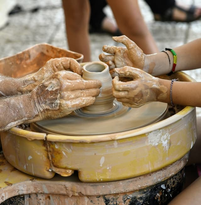 two pairs of hands at opposite sides of a pottery wheel making clay potter together to signify relationship with parents