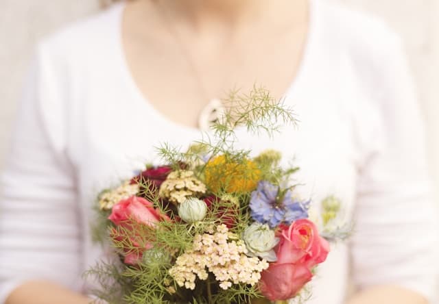 woman in white shirt holding a bouquet of flowers