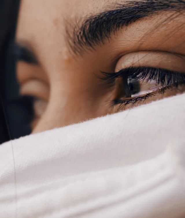 closeup of woman's eyes with tears in them, black eyebrows and lashes